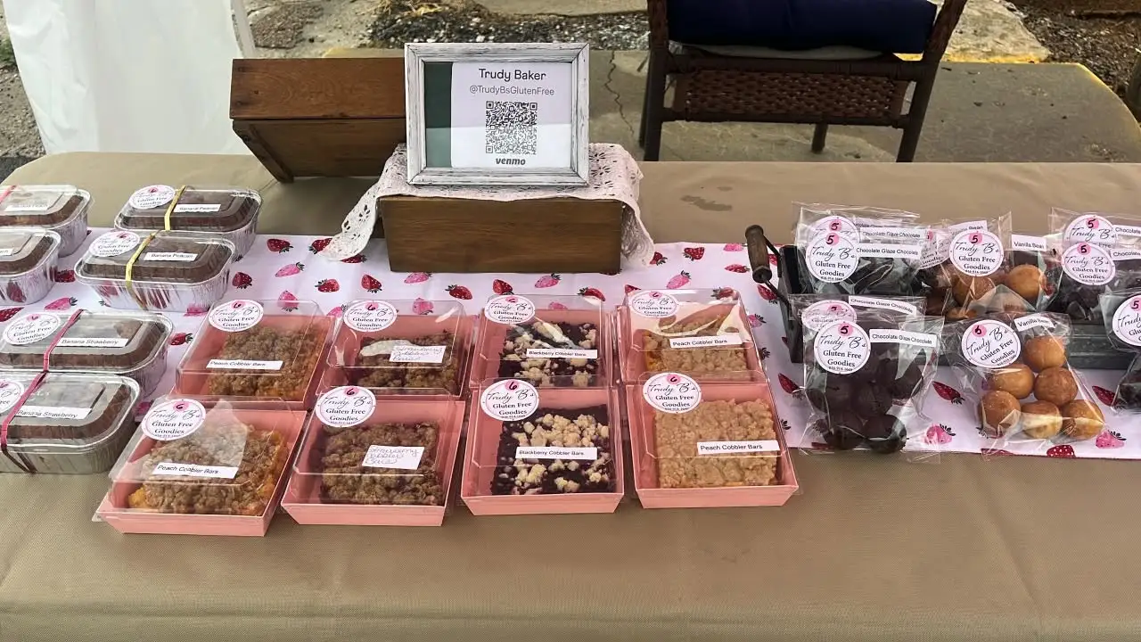 Trudy B's table spread of cobbler bars, banana bread, and bite-size goodies at a farmers market